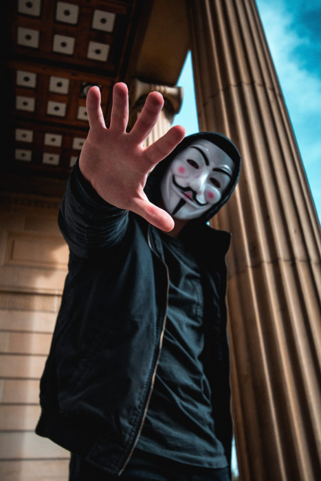 man wearing Guy Fawkes Mask standing inside building person 2k