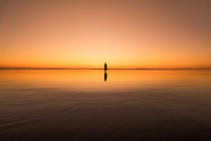 calm body of water silhouette photo person standing above 2k
