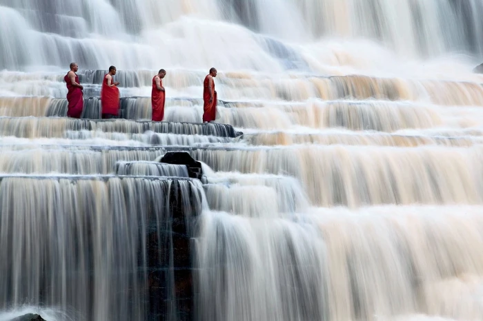 four person walking across waterfalls nature landscape people