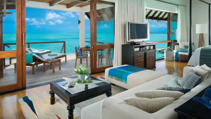 Inside Of Water Bungalow Four Seasons Maldives white fabric sofa set black wooden coffee maker and brown dresser 2k