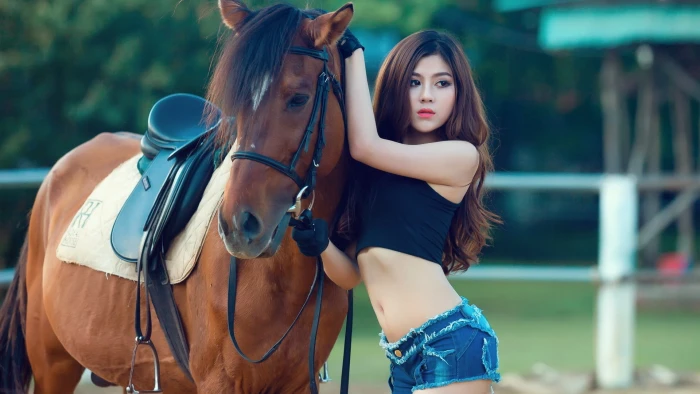 women's black crop top woman standing in front of brown horse 2k