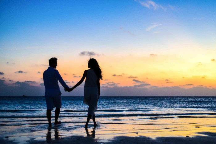 Man and Woman Holding Hands Walking on Seashore during Sunrise 2k