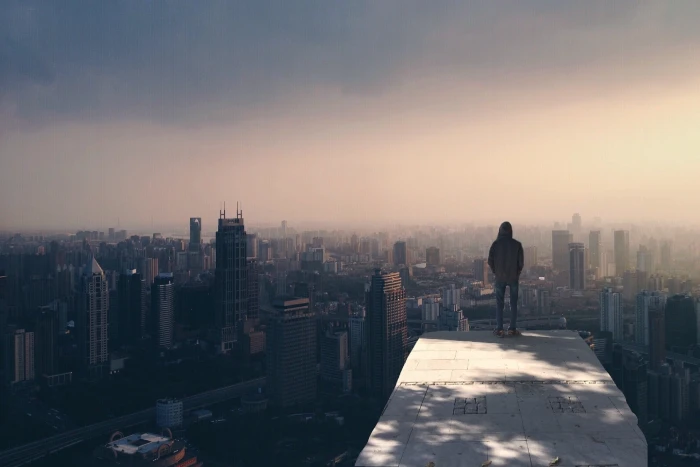 person stand on clif rock under blue skies during daytime city 2k