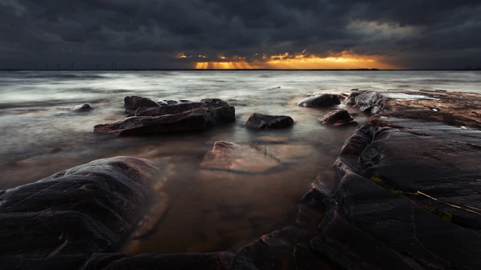 body of water nature landscape rock clouds storm sun rays 2k