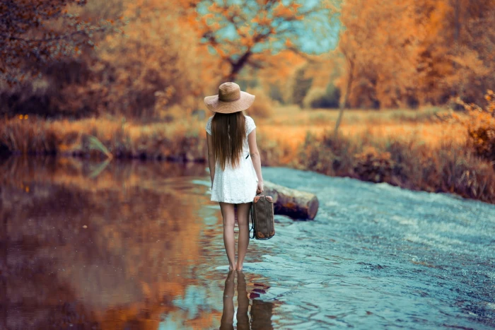women's white cap sleeved mini dress woman walking on shallow body of water carrying suitcase under shad tree at daytime 2k