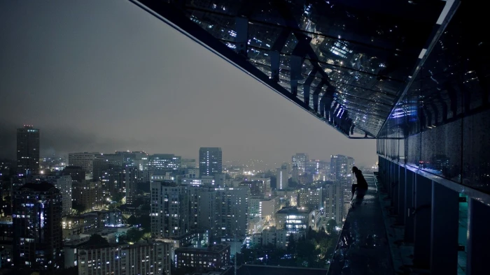 gray high rise buildings person standing near rails of building rooftop 2k