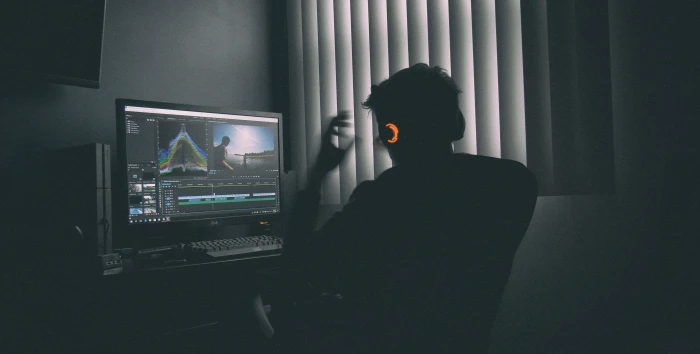 shallow focus photography of man listing to music in front the computer person sitting on chair while looking monitor beside window with blinds during daytime 2k 4k