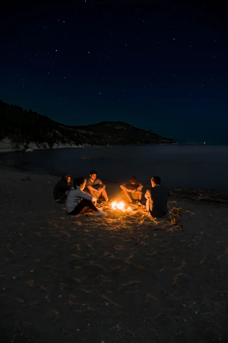 people sitting near campfire seashore bonfire during nighttime 2k 4k