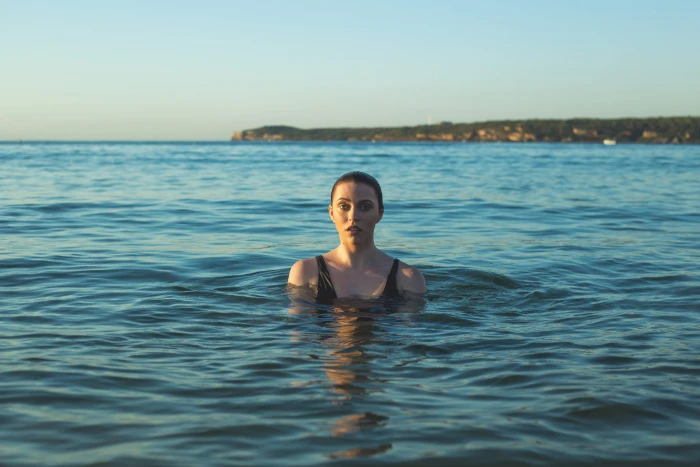 woman wearing black tank top swimming on sea at daytime beach 2k 4k 5k