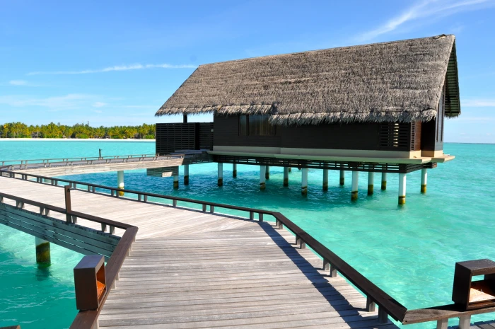 brown wooden house in body of water under blue sky maldives 2k 4k