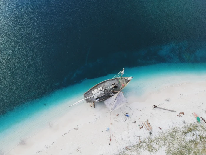 aerial photo of boat on seashore during daytime high angle gray and white fishing 2k 4k