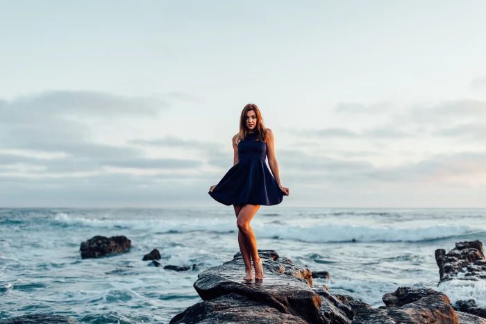 woman in black dress shirt on sea stone formation during daytime 2k 4k 5k