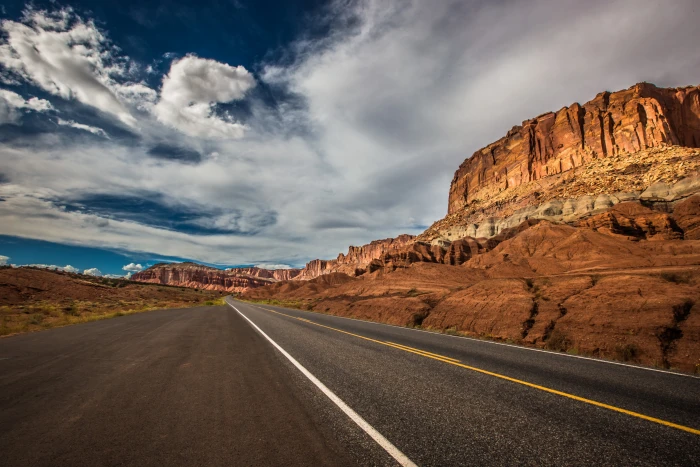 brown concrete roadway near mountain under white clouds at daytime 2k 4k 5k