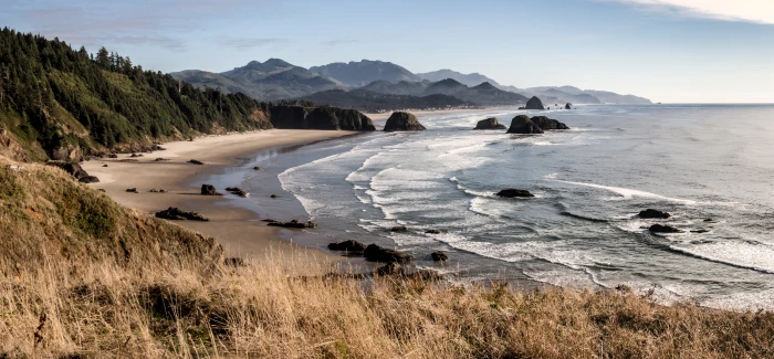 sea shore near mountains under blue skies at daytime cannon beach 2k 4k 5k
