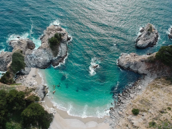 aerial view of beach with rock mountain during daytime drone 2k 4k