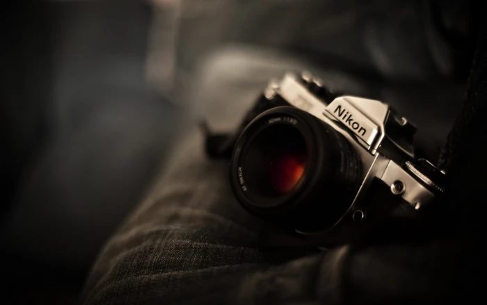 black and grey Nikon reel camera DSLR on person s lap 2k