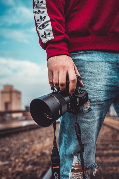 person holding black Sony DSLR camera man male hand lens 2k 4k