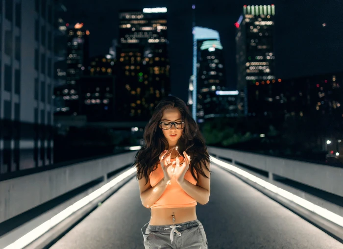 woman in orange crop top the middle of street during night time 2k