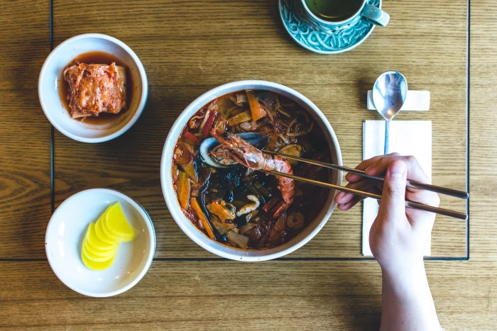 Eating Korean seafood stew hands soup top view wood chopsticks 2k 4k 5k