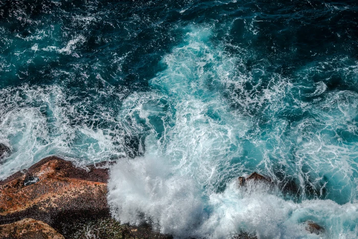 aerial photography of ocean photo body water beside rock during daytime 2k 4k 5k