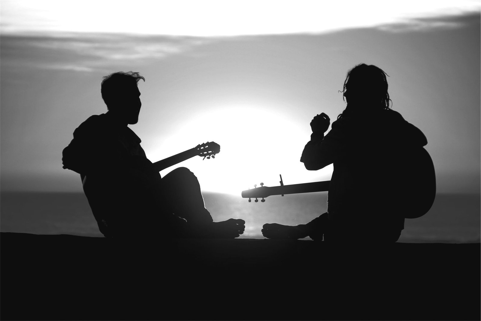 silhouette photography of two men playing guitar near body water 2k