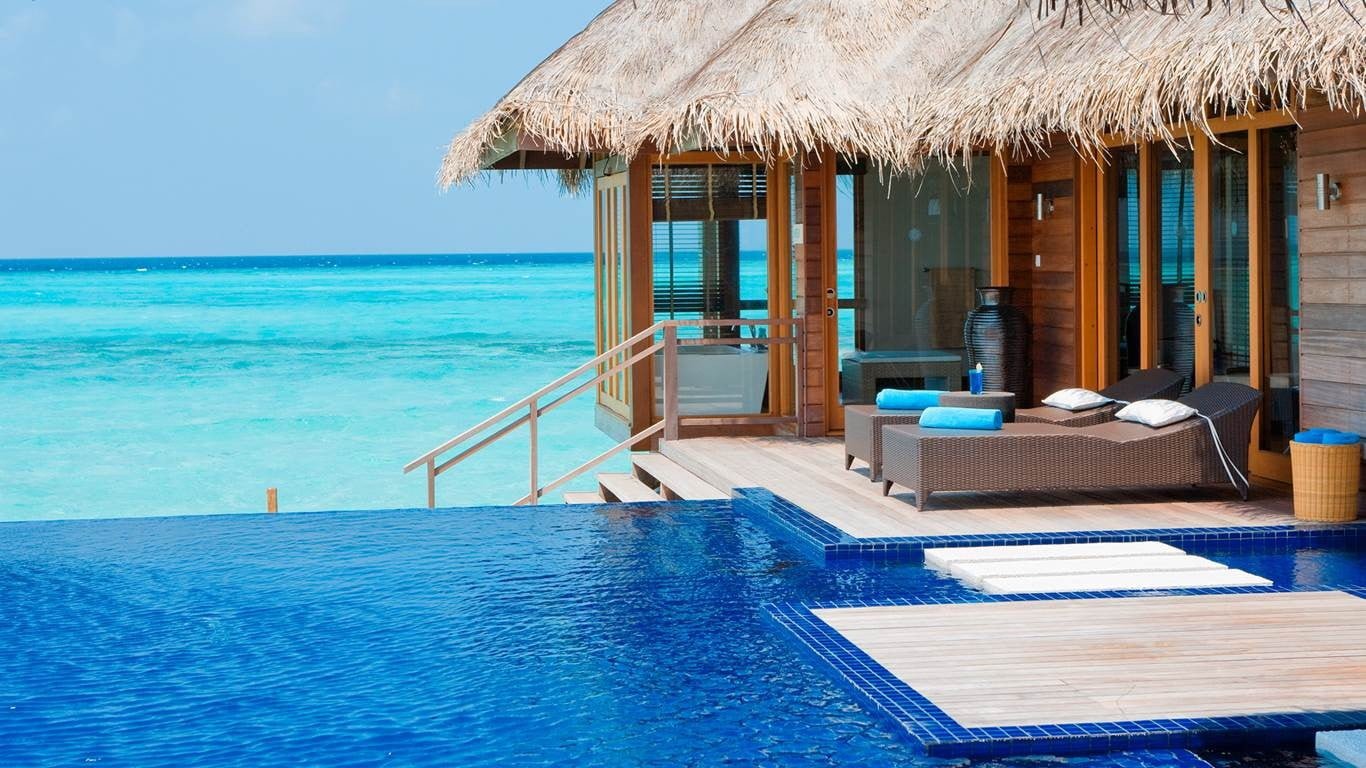brown wooden floating cottage Maldives resort swimming pool