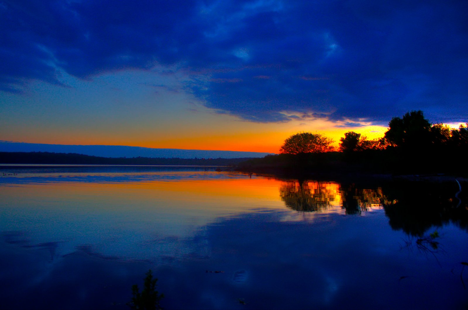 calm body of water during golden hour sunset lake trees orange 2k