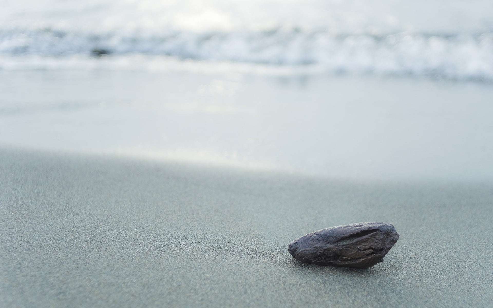 gray stone fragment on top of white surface beach nature sand 2k