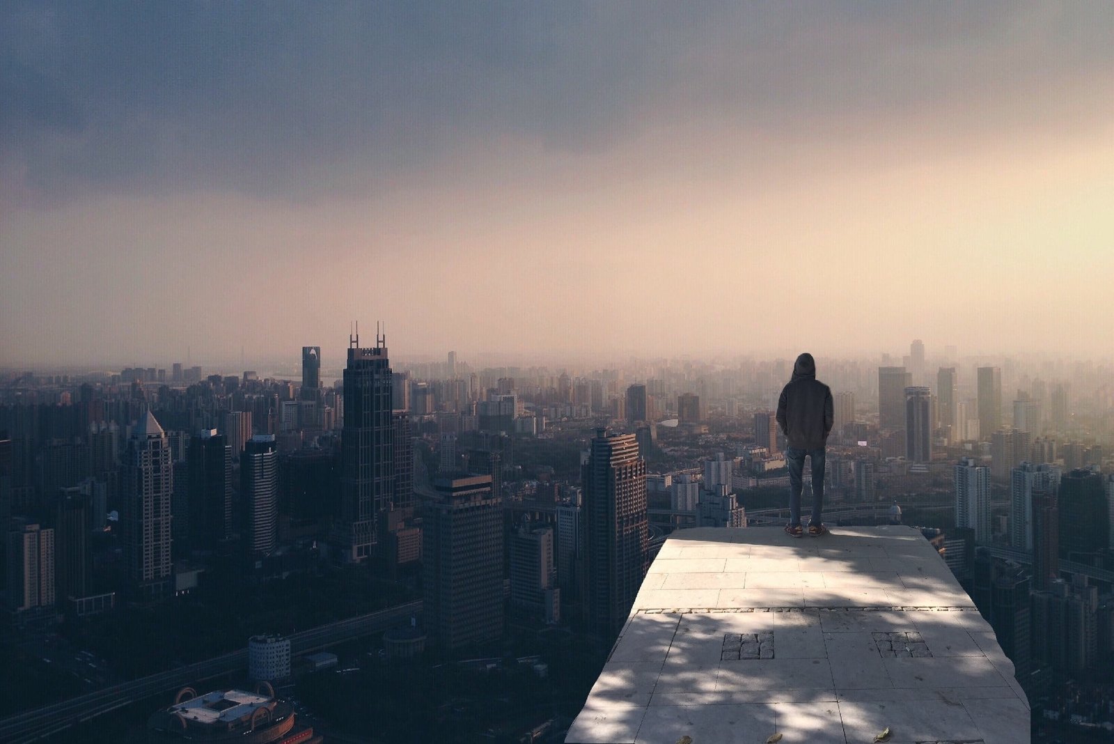 person stand on clif rock under blue skies during daytime city 2k