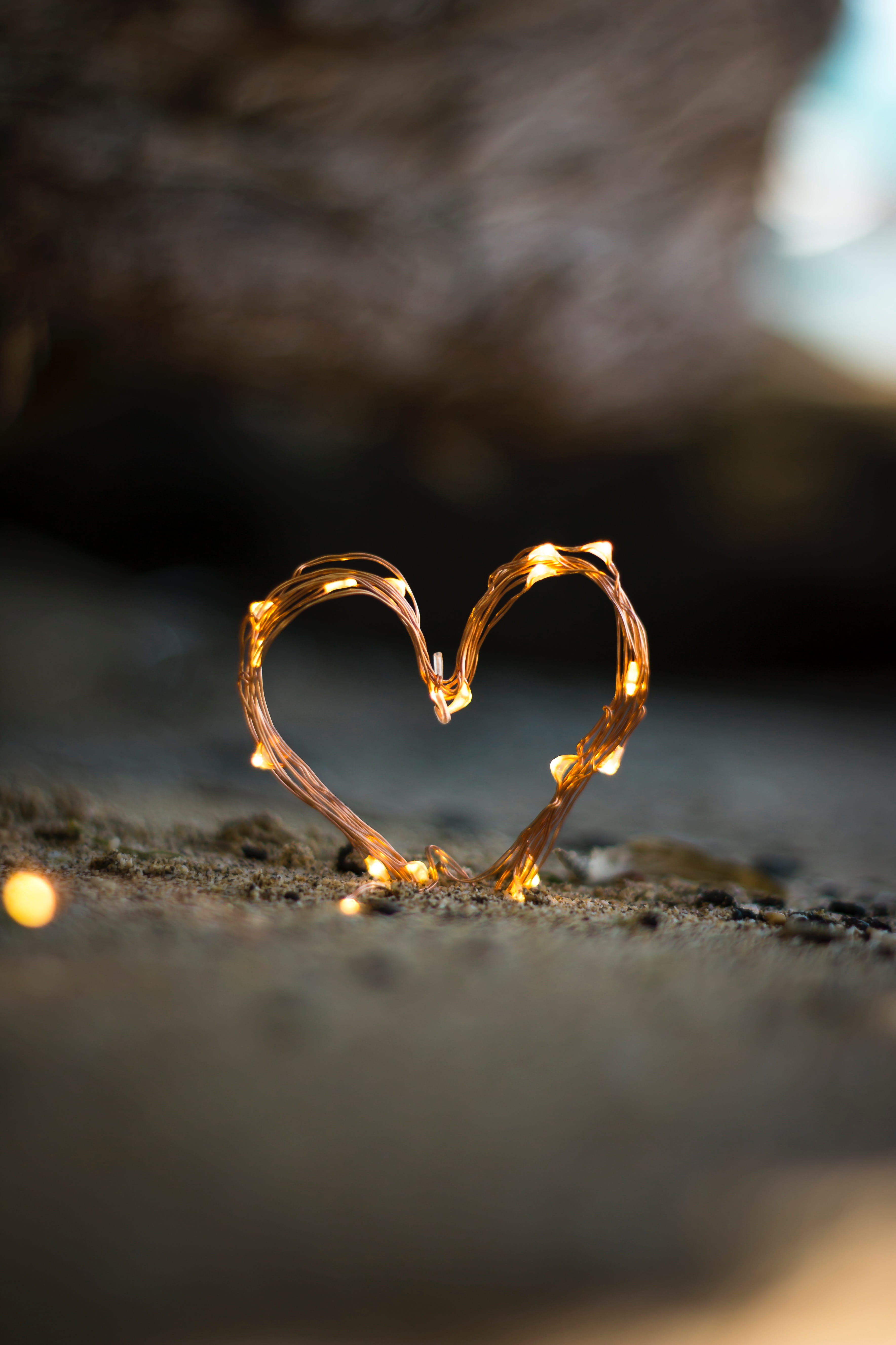 close up photography of heart shaped fairy lite on brown sand 2k 4k