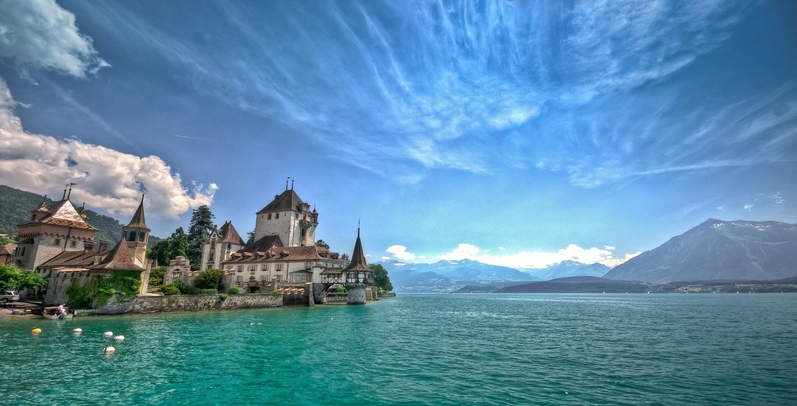 white concrete building beside body of water lake mountains 2k