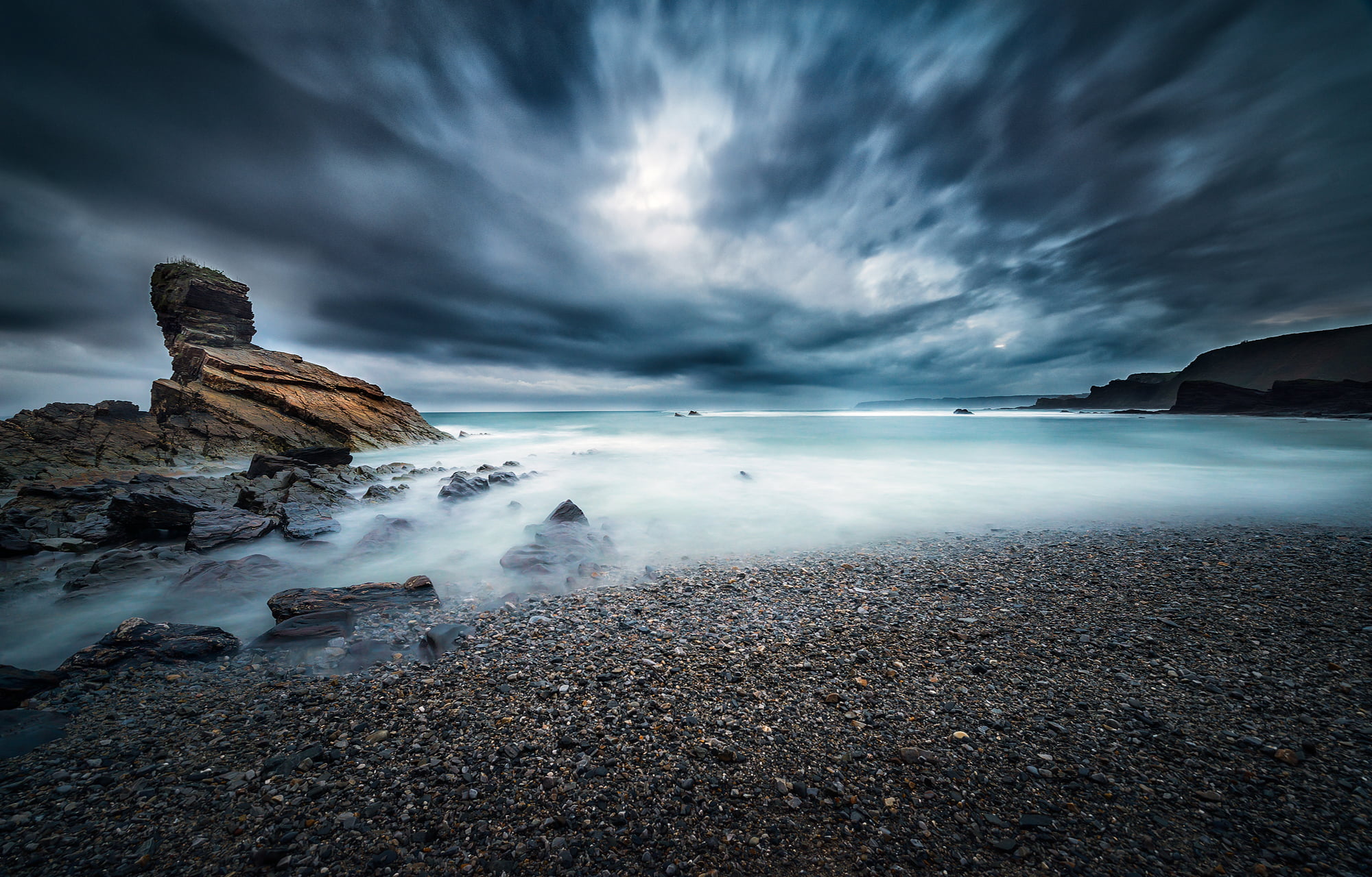 stones on seashore under clouded sky Alone in the dark landscape 2k