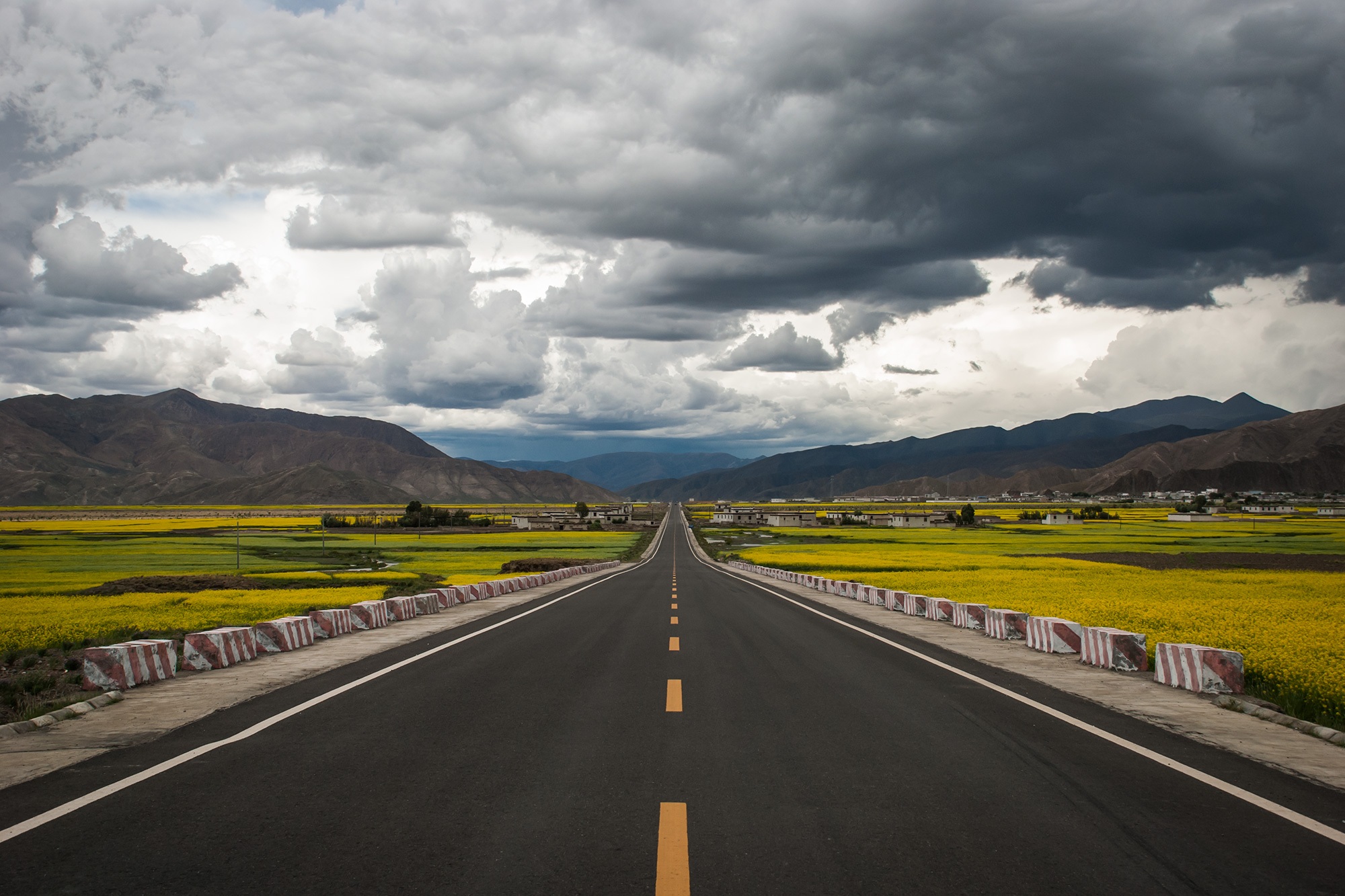 gray concrete road between grass fields under cumulus clouds 2k