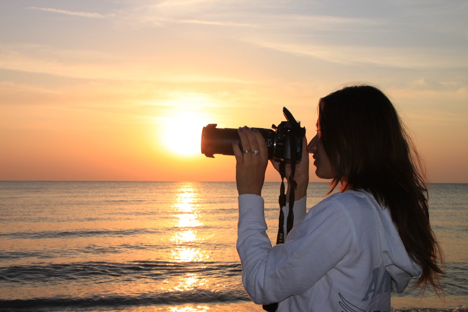 woman holding DSLR camera near beach during golden hour female 2k 4k 5k