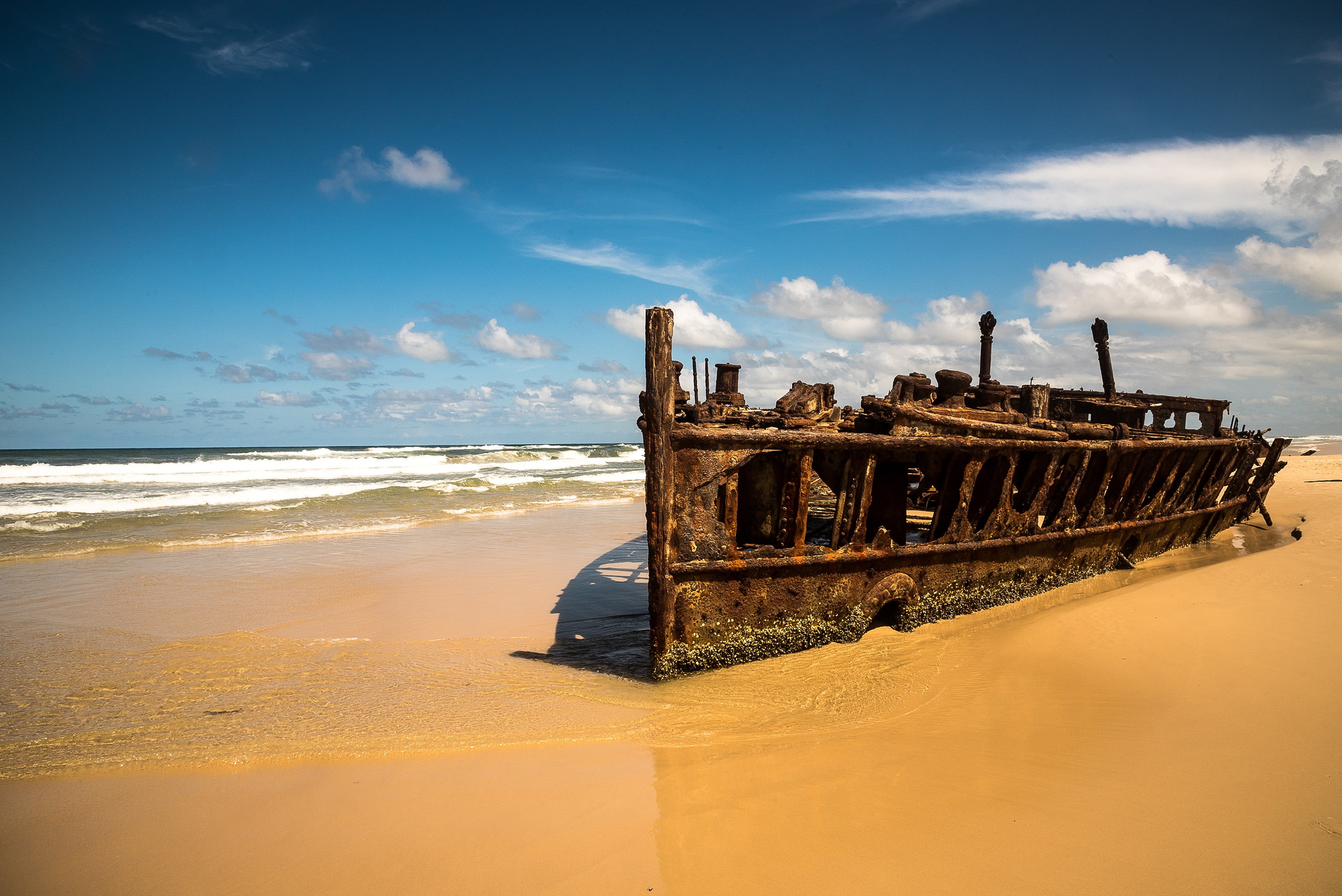 brown shipwreck photo beach sea clouds blue sky boat sand 2k
