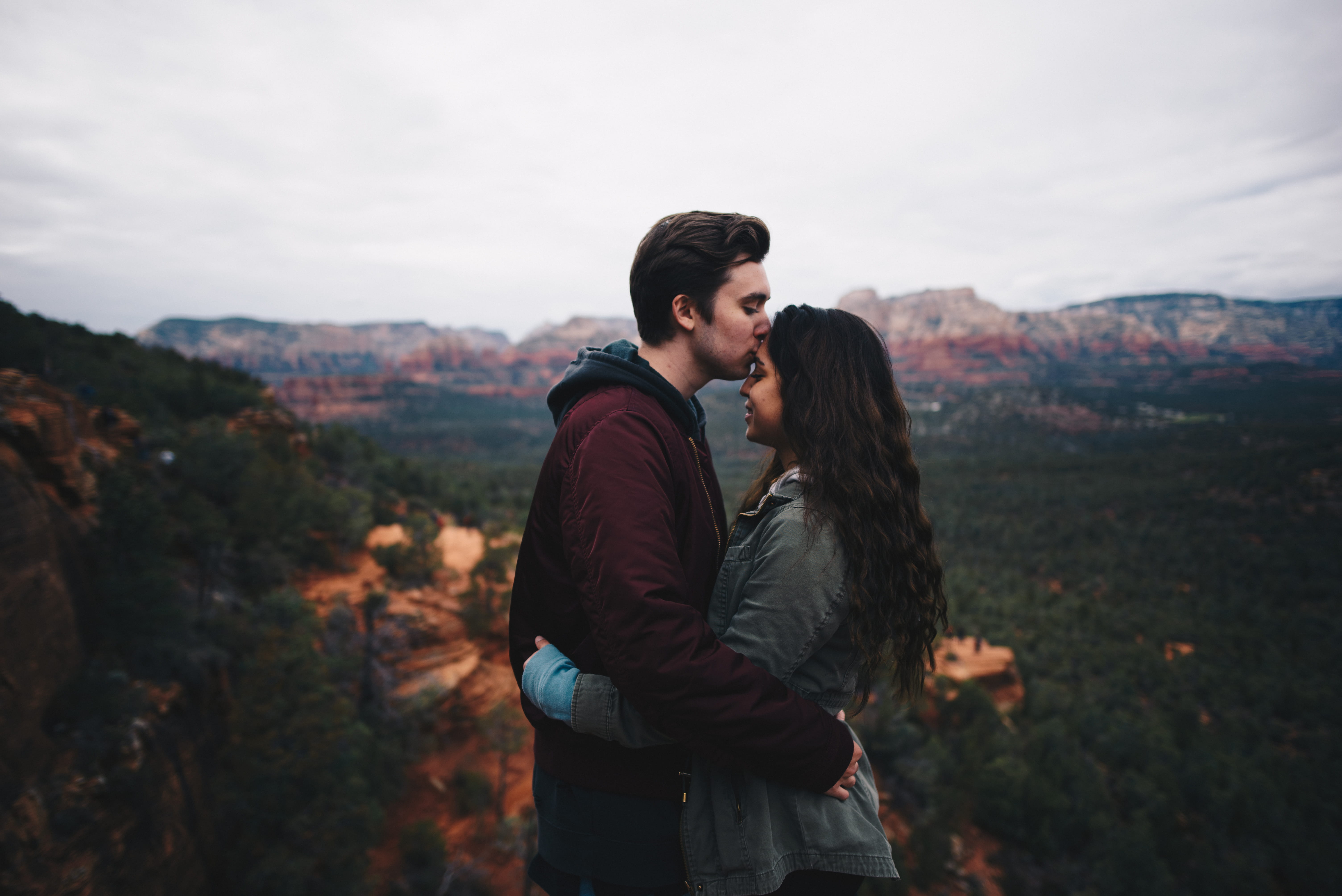 man kissing woman s forehead at top of mountain beside range 2k 4k 5k