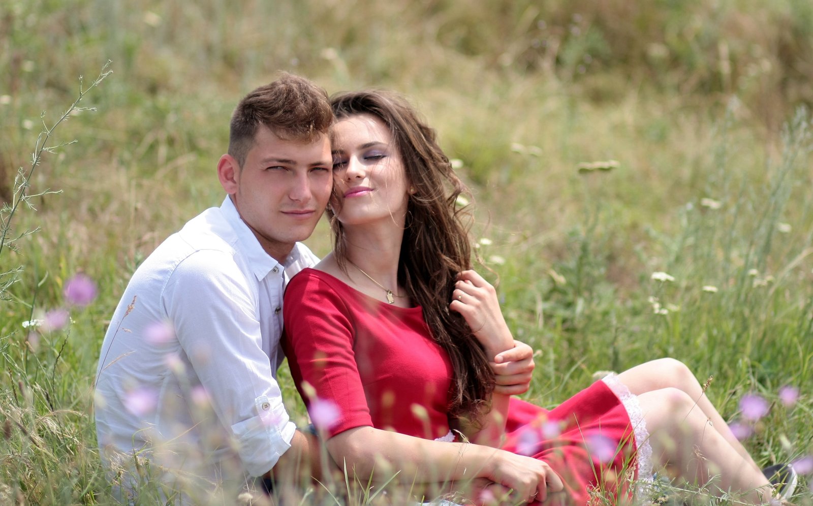 woman and man near each other while sitting on grass field during daytime 2k 4k