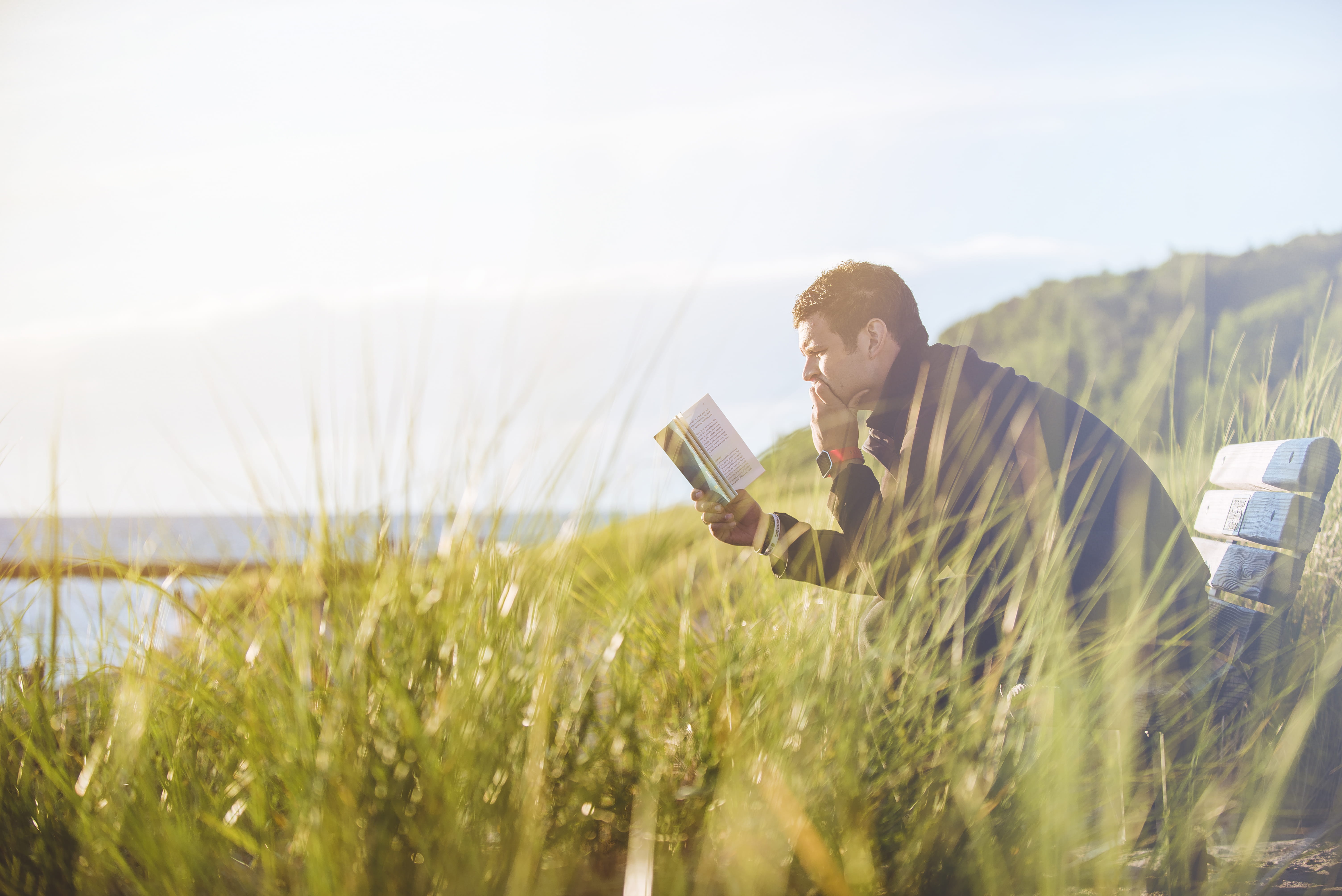man reading book on beach near lake during daytime sitting bench 2k 4k 5k