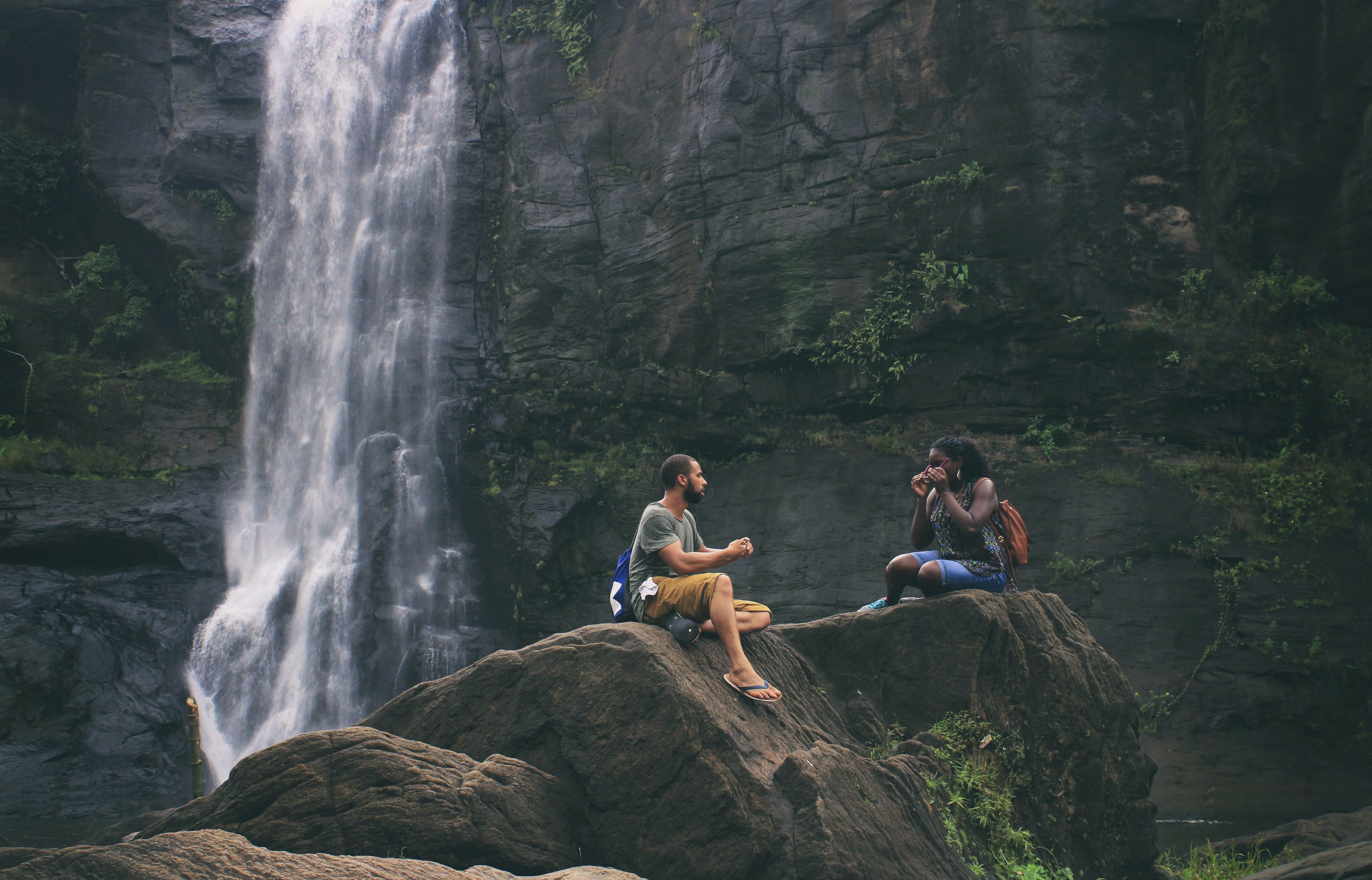 people sitting on rock near waterfalls Love Couple Woman young 2k 4k 5k