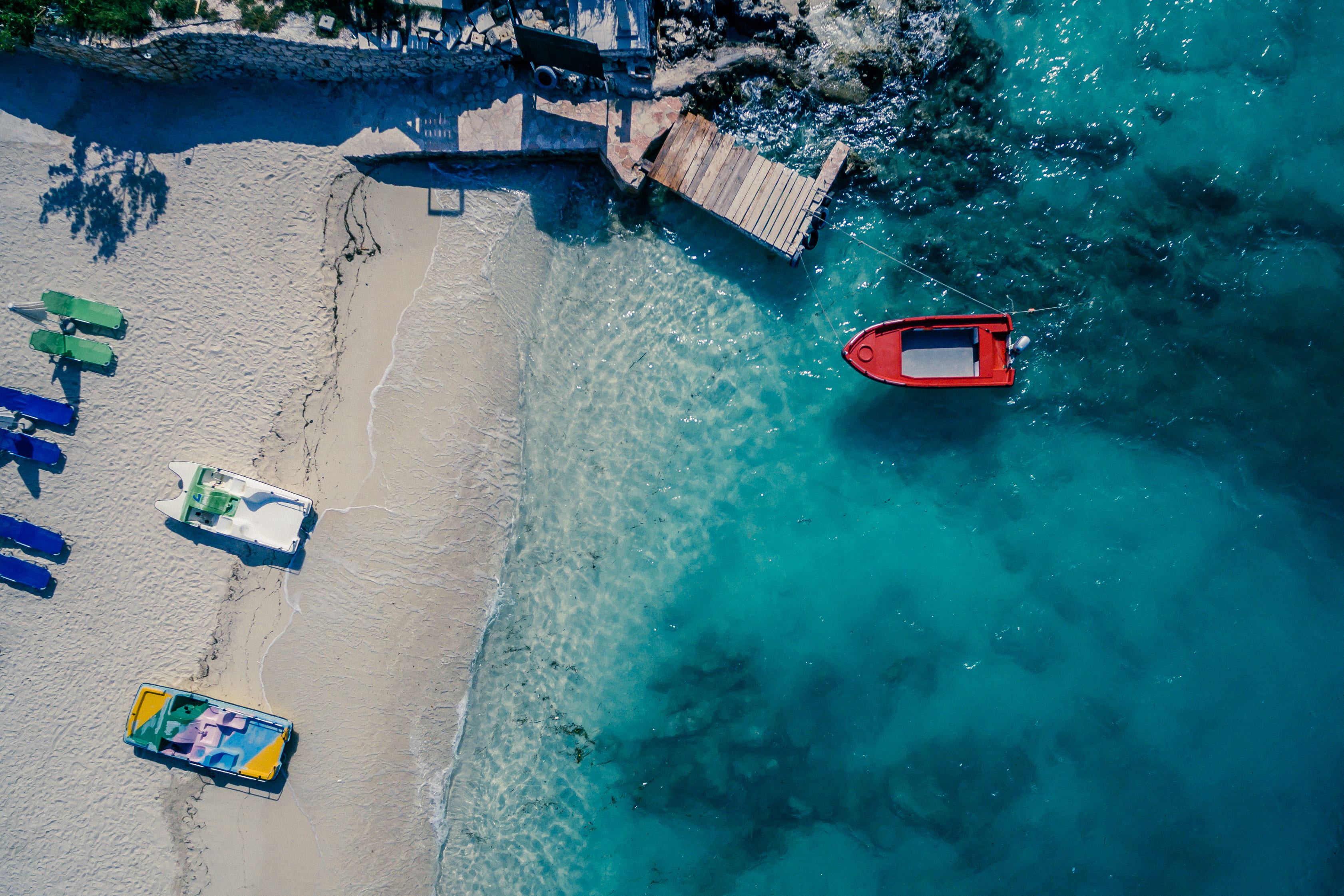 red boat on body of water near brown wooden foot board aerial view 2k