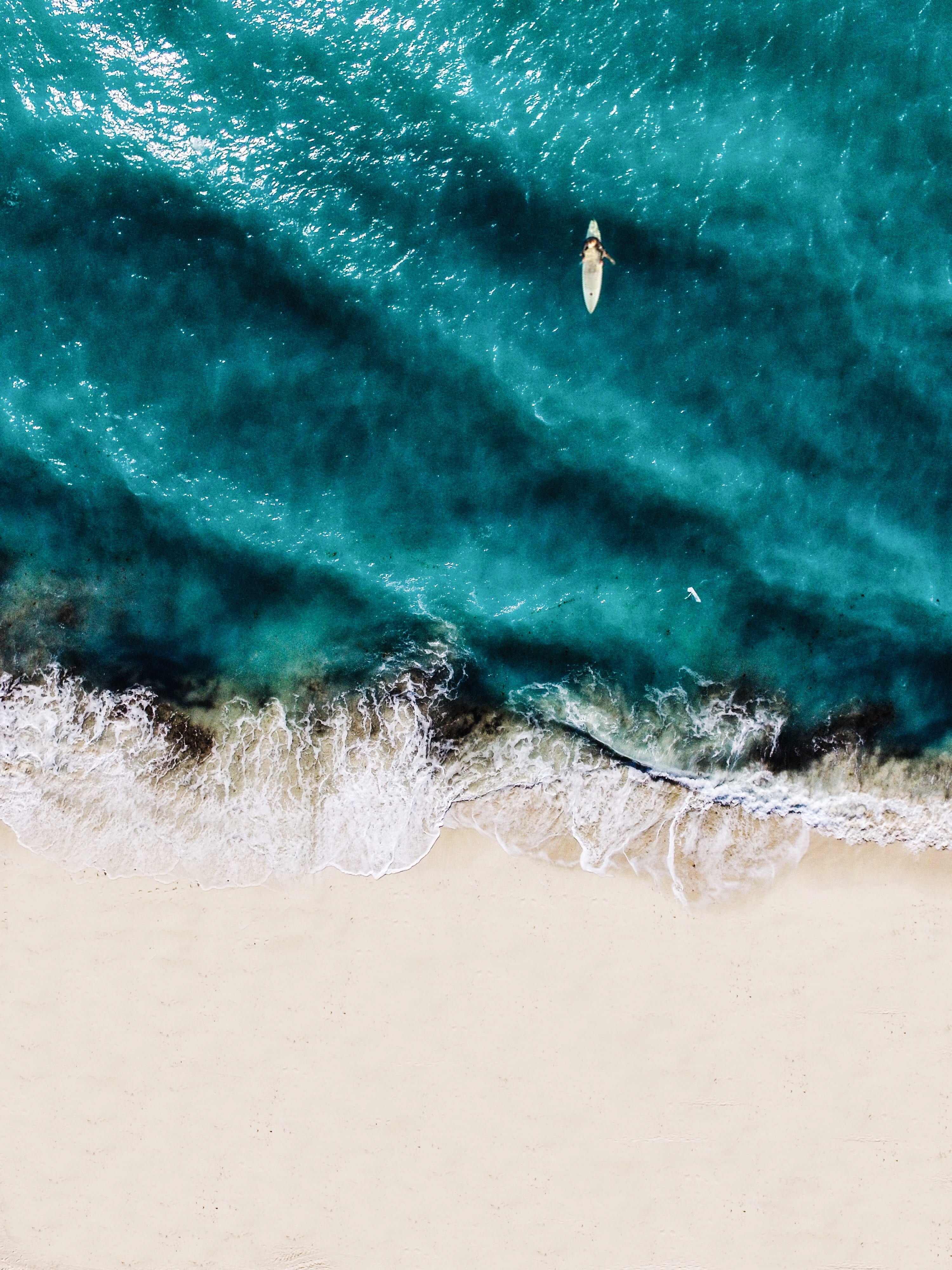 beach from above aerial photo of person riding surfboard on bodies water 2k