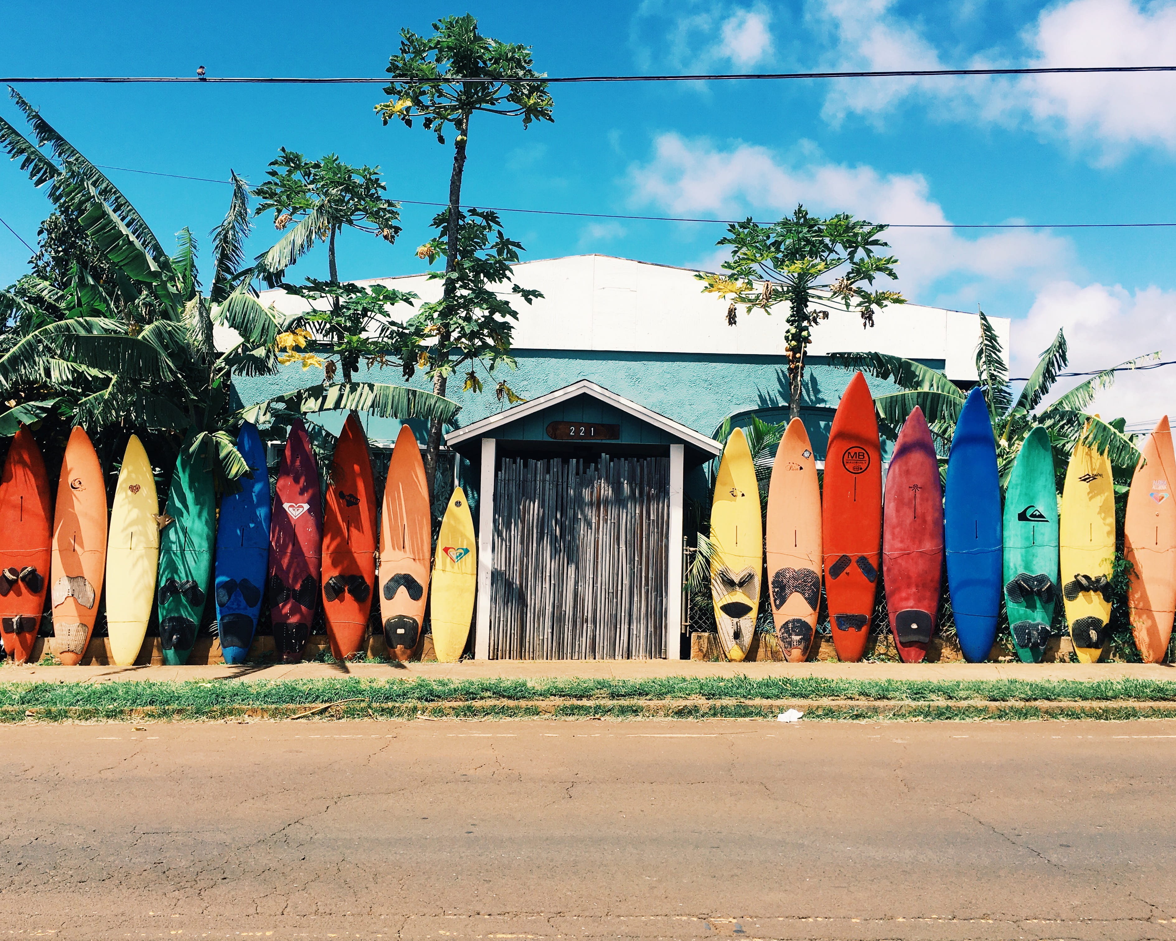 blue and white house surrounded by surfboards during daytime longboard surfboard beside 2k 4k