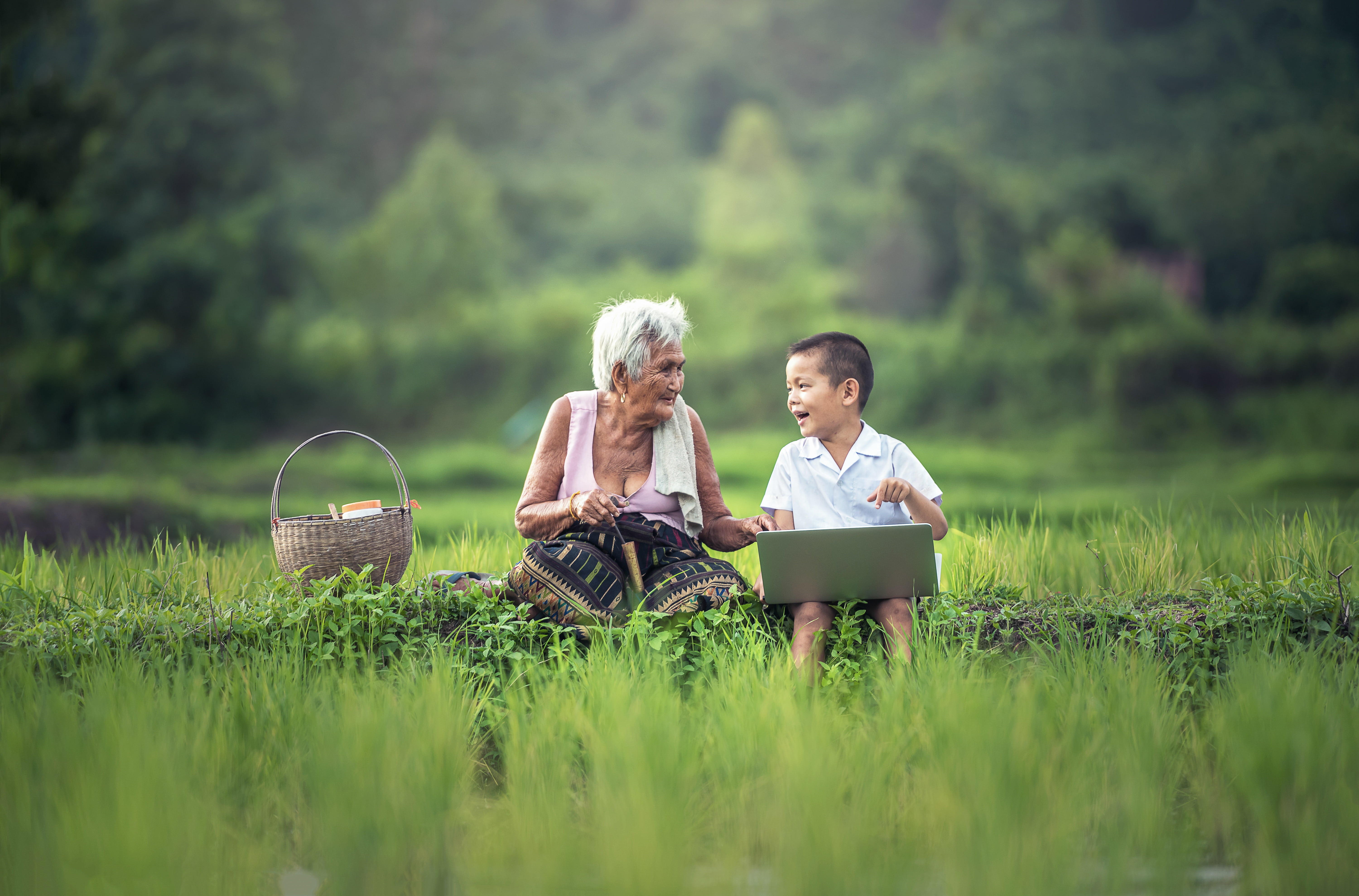 boy with laptop sitting beside white haired woman on green field 2k 4k 5k