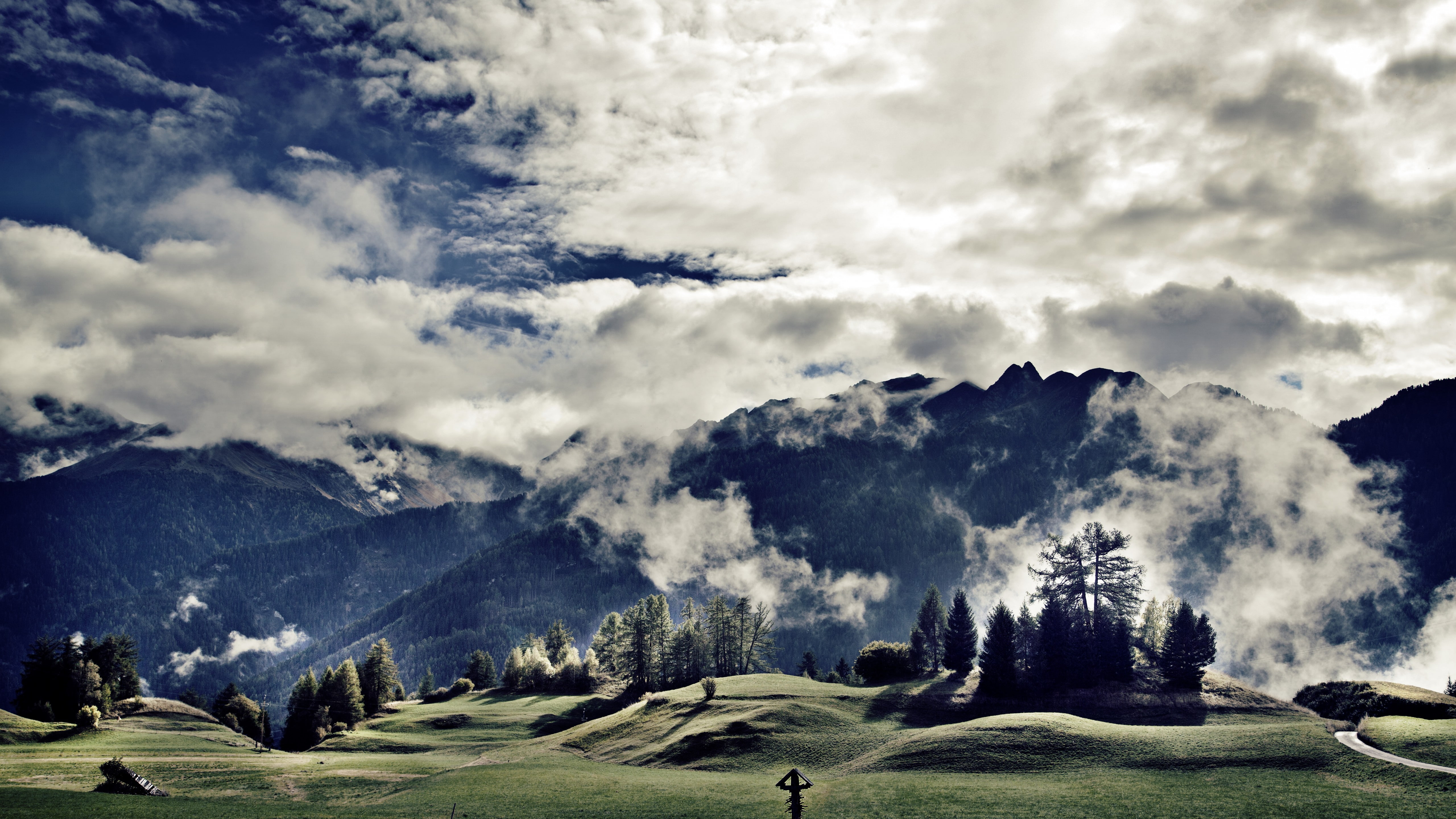 green grass lawn with trees near mountain under blue and white cloudy sky 2k 4k 5k