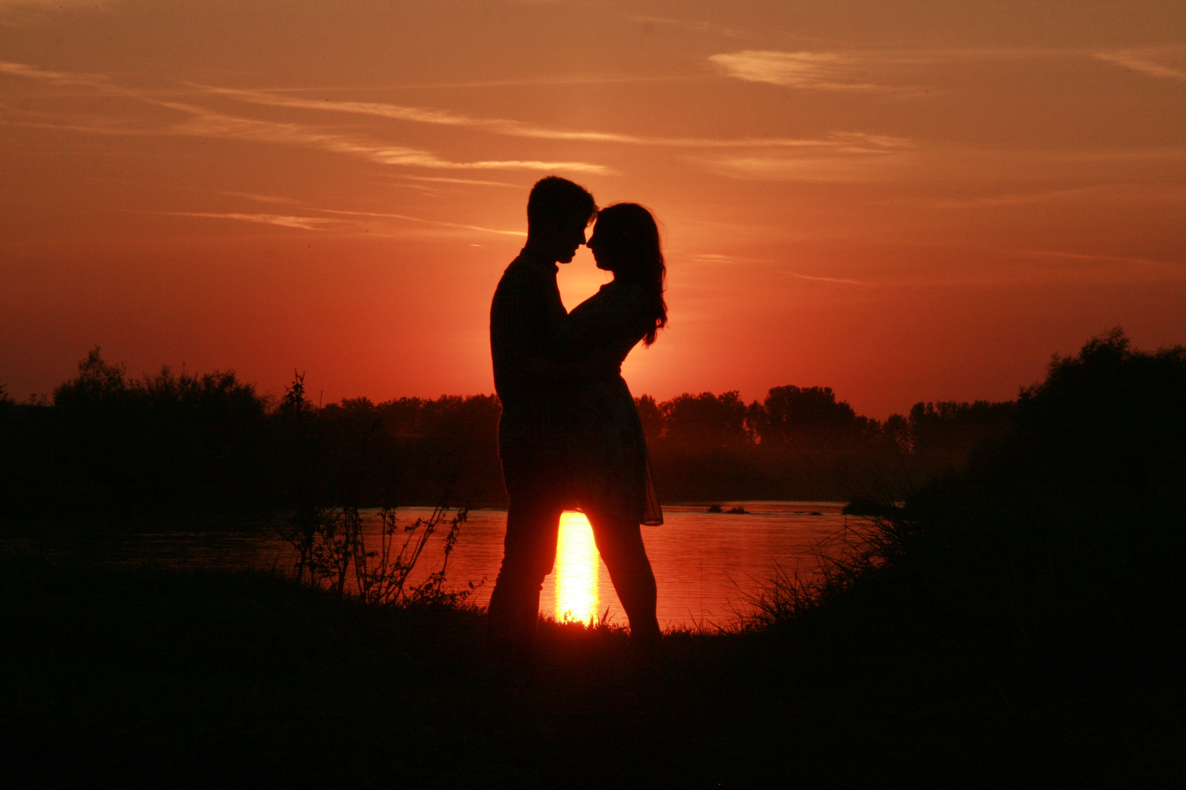 silhouette of couple standing beside body water against sun ray 2k 4k