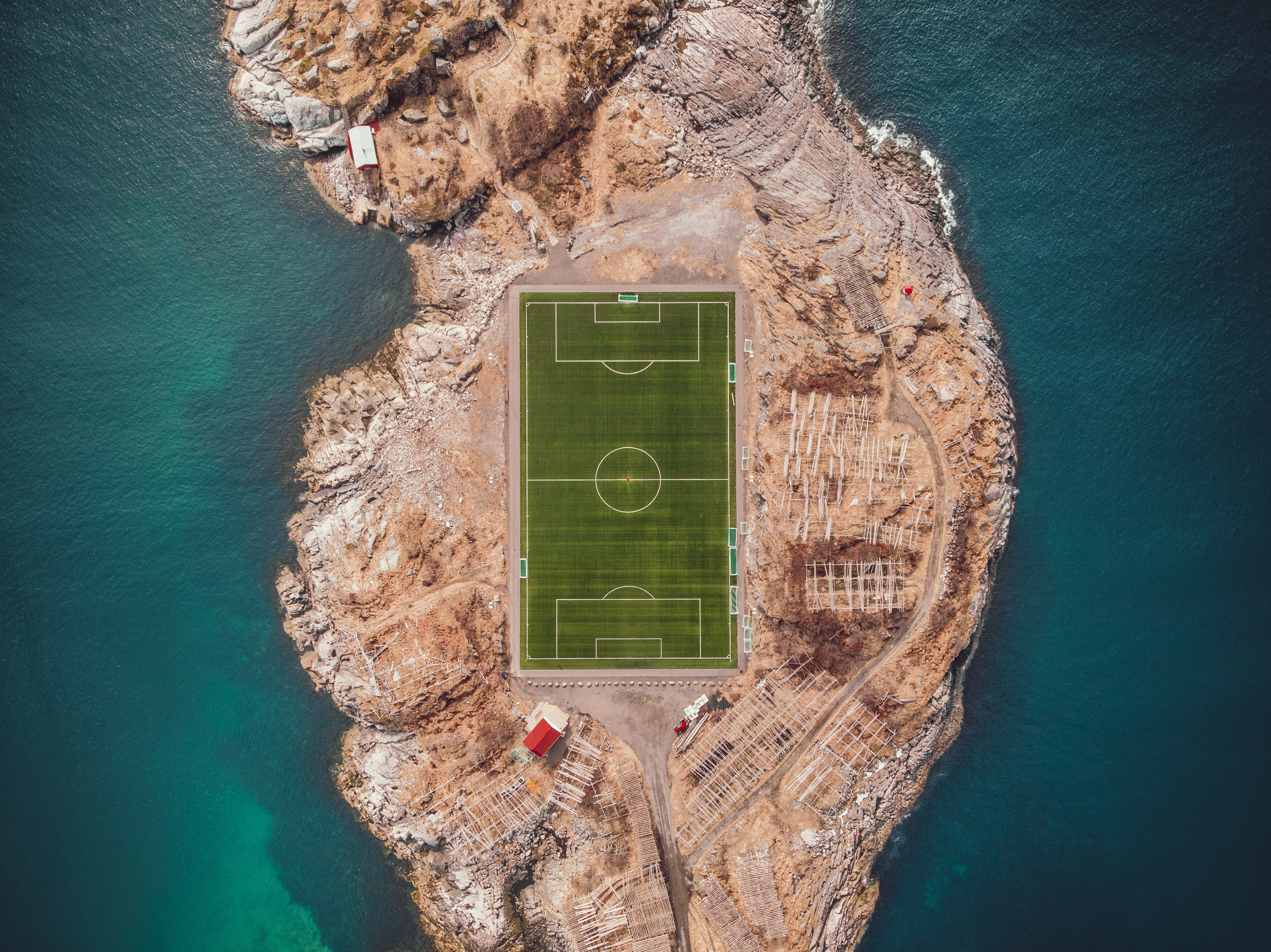 aerial photography of soccer field near body water bird s eye island with in the middle 2k 4k