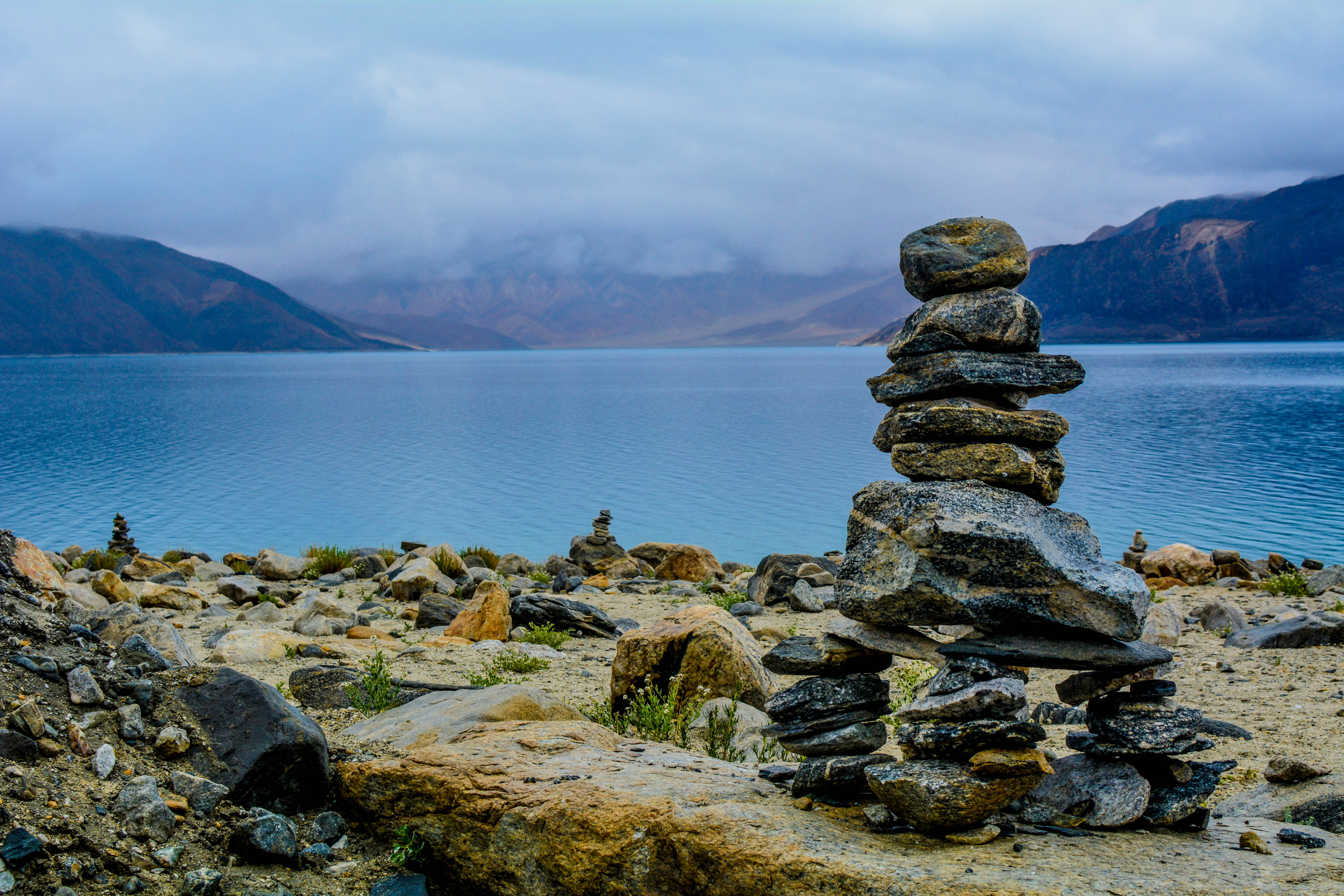 gray rocks stacks on brown surface balance stone near body of water 2k 4k 5k