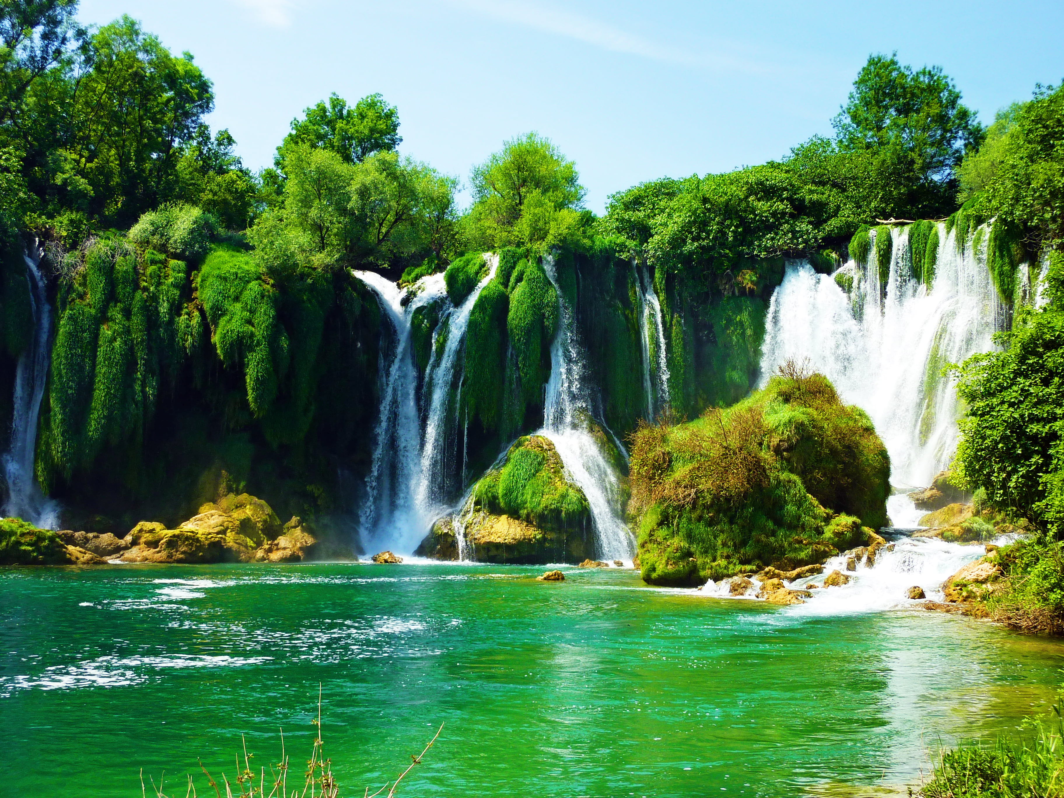 green grasses growing on rocks in waterfalls at daytime Kravice 2k 4k
