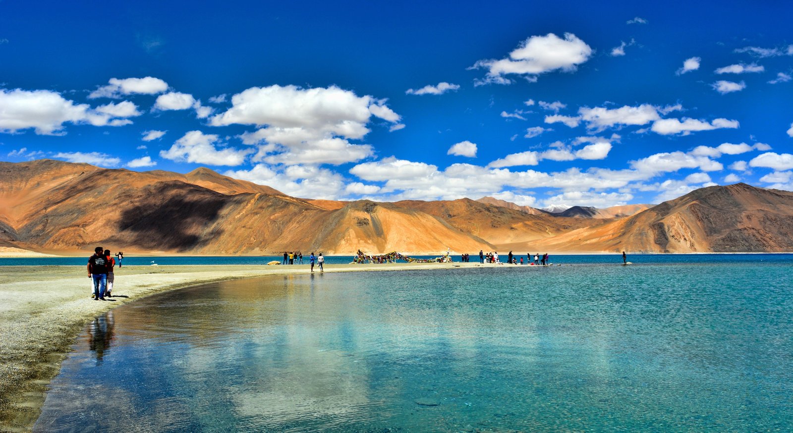 person walking on pathway beside body of water during daytime 2k 4k 5k