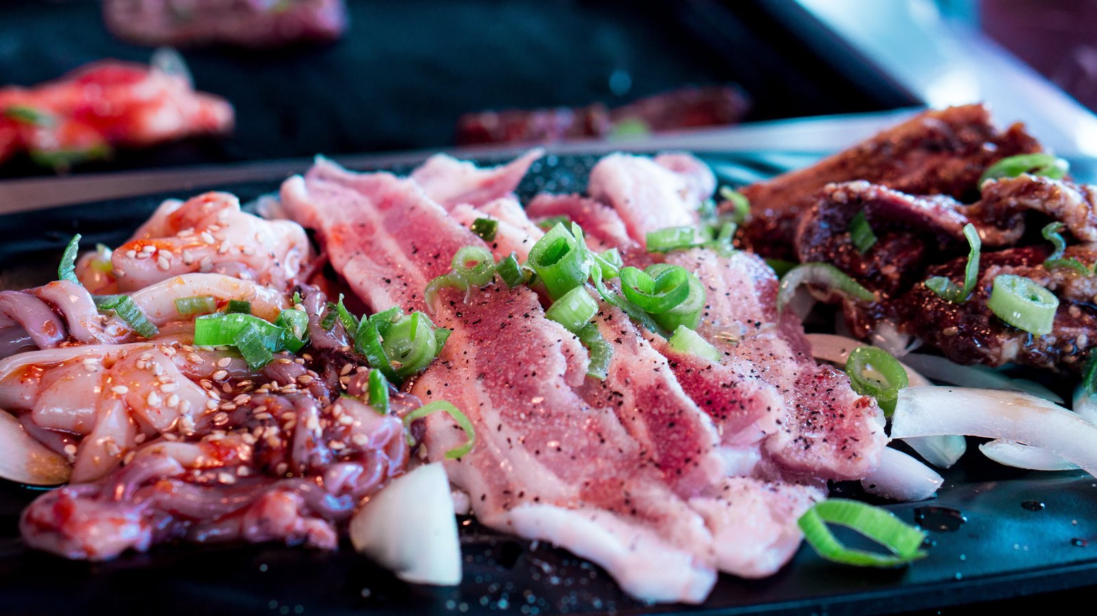 raw meat and octopus tentacles on black surface barbecue korean bbq 2k 4k 5k